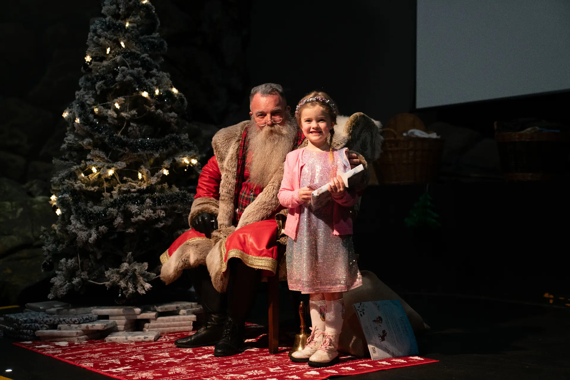 Santa with a child by the Christmas tree